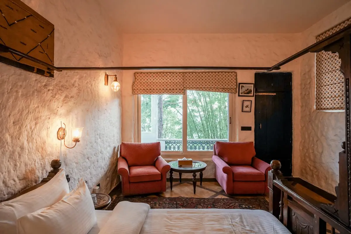 Armchairs by the garden-view window in the Deluxe Valley Room at Two Chimneys, near Nainital
