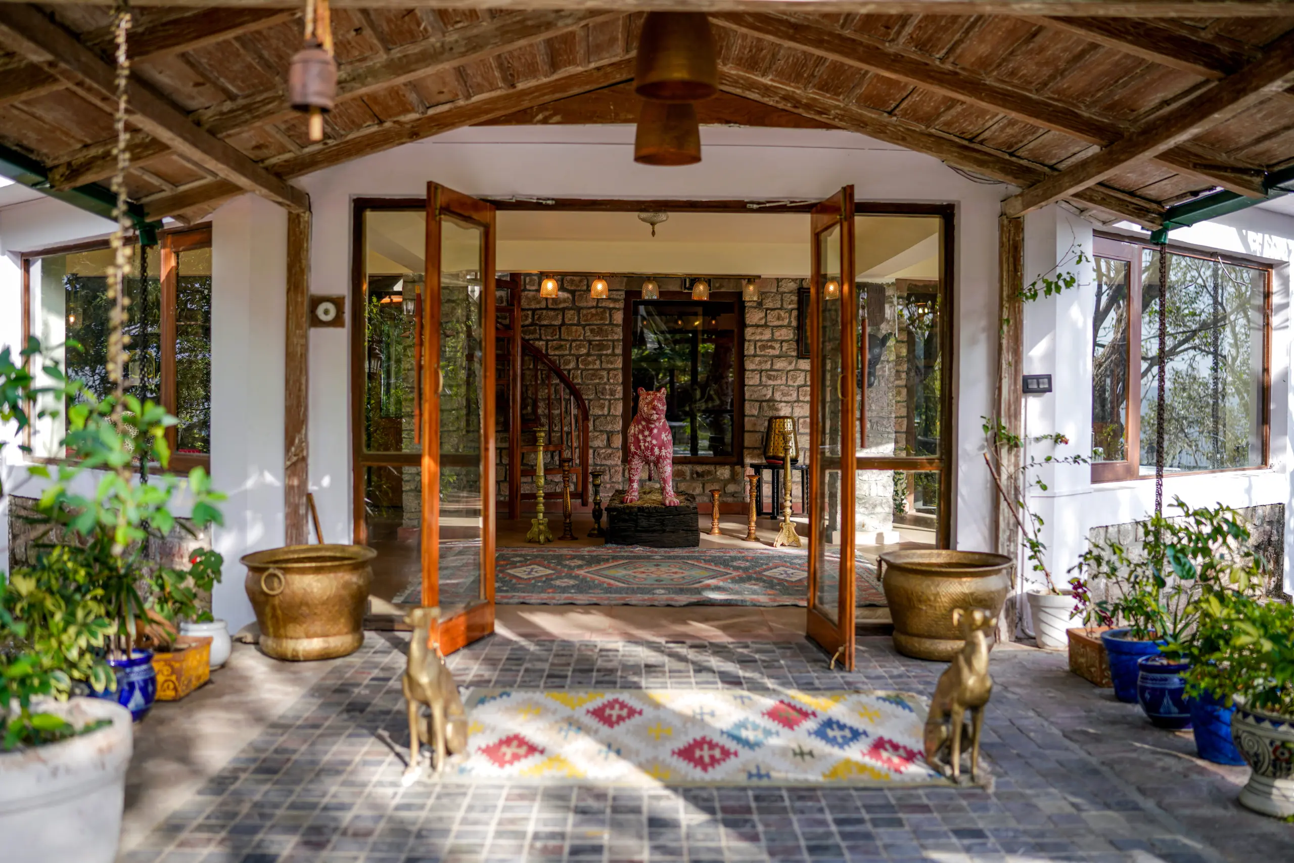 Open veranda entrance with brass deer and planters at Two Chimneys heritage bungalow, Gethia