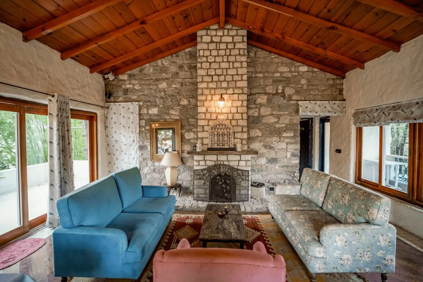 Stone fireplace lounge with sofas inside the heritage bungalow at Two Chimneys, Gethia