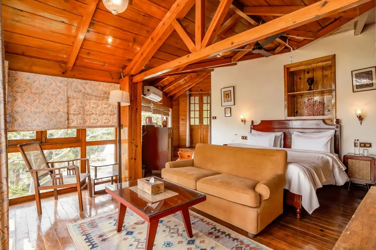 Sitting area and bed under exposed wooden beams in the Superior Cottage Room, Two Chimneys