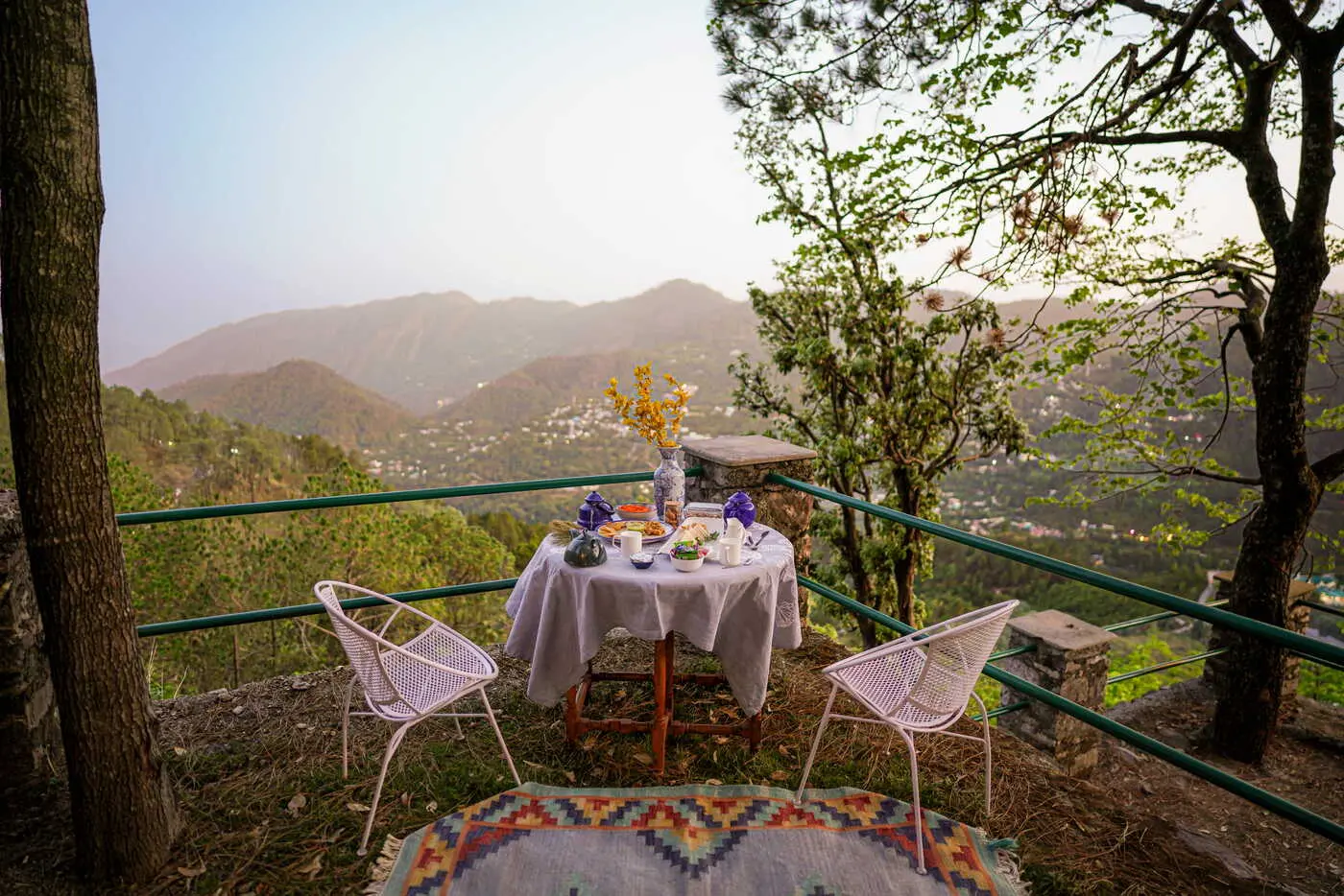 Breakfast table set on a cliff edge overlooking Kumaon valleys at Two Chimneys, Gethia